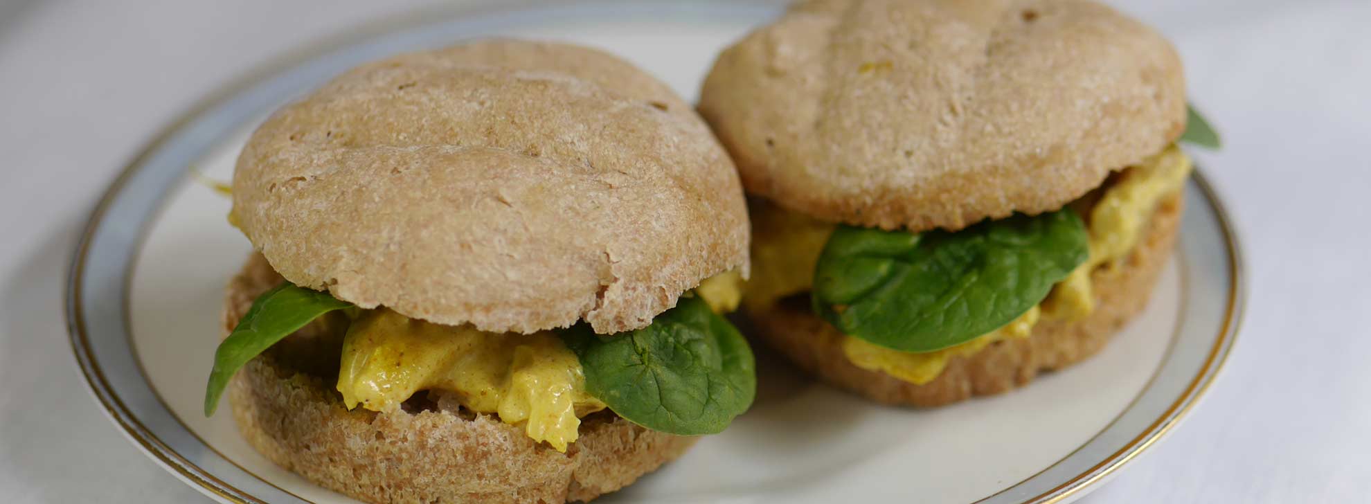 two small buns with curried chicken filling and baby spinach leaf garnish