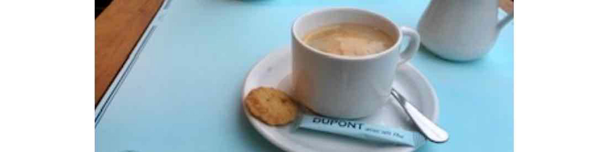 cup  of coffee with small biscuit and spoon on saucer