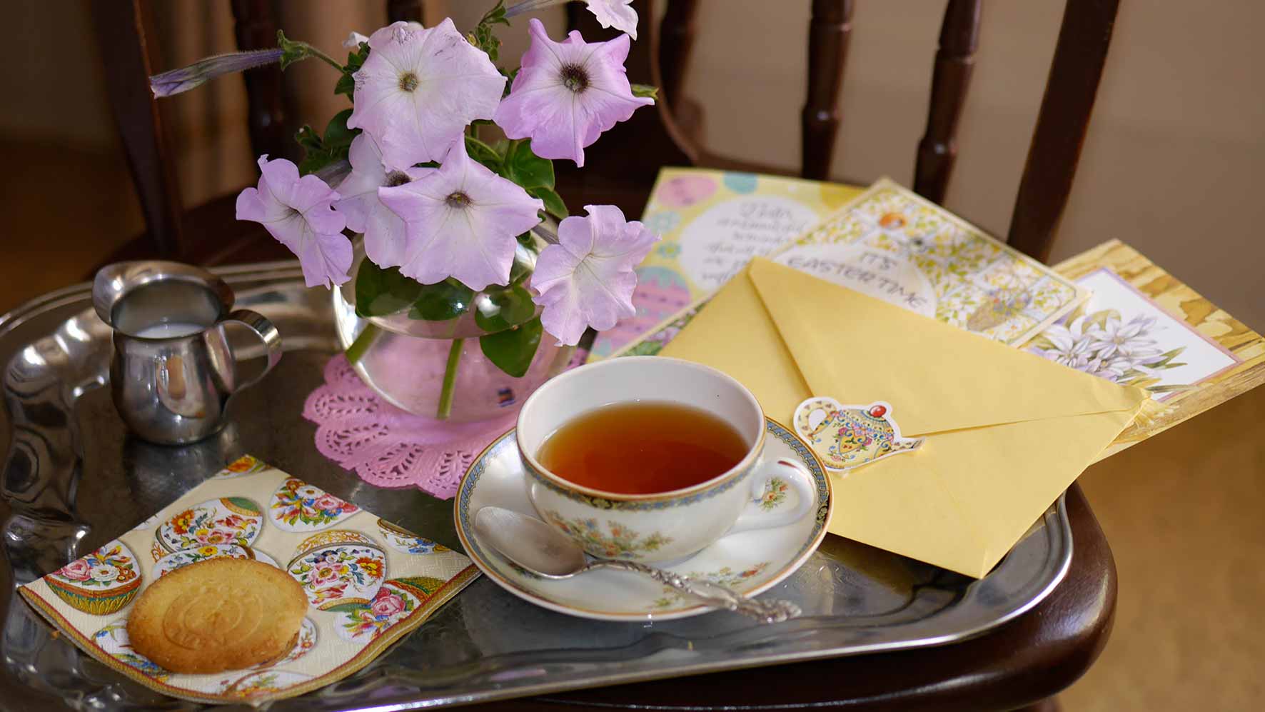 Tea tray with Easter themed napkins, tea, flowers and Easter greeting cards.