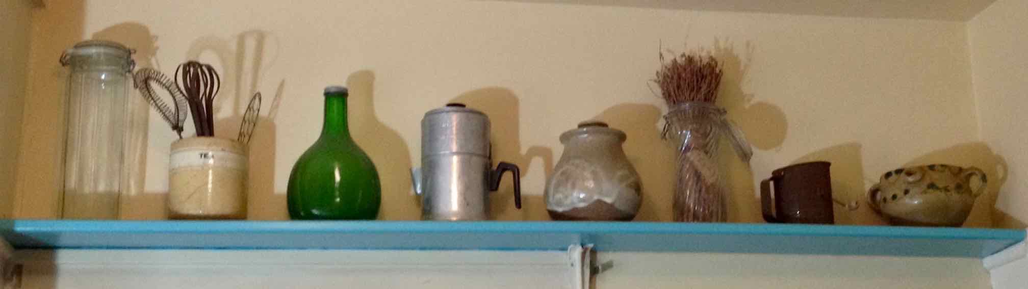 assortment of kitchen shelf items including antique tea cannister holding antique egg beaters, a cannister of Provence lavender and a Tunisian water pitcher
