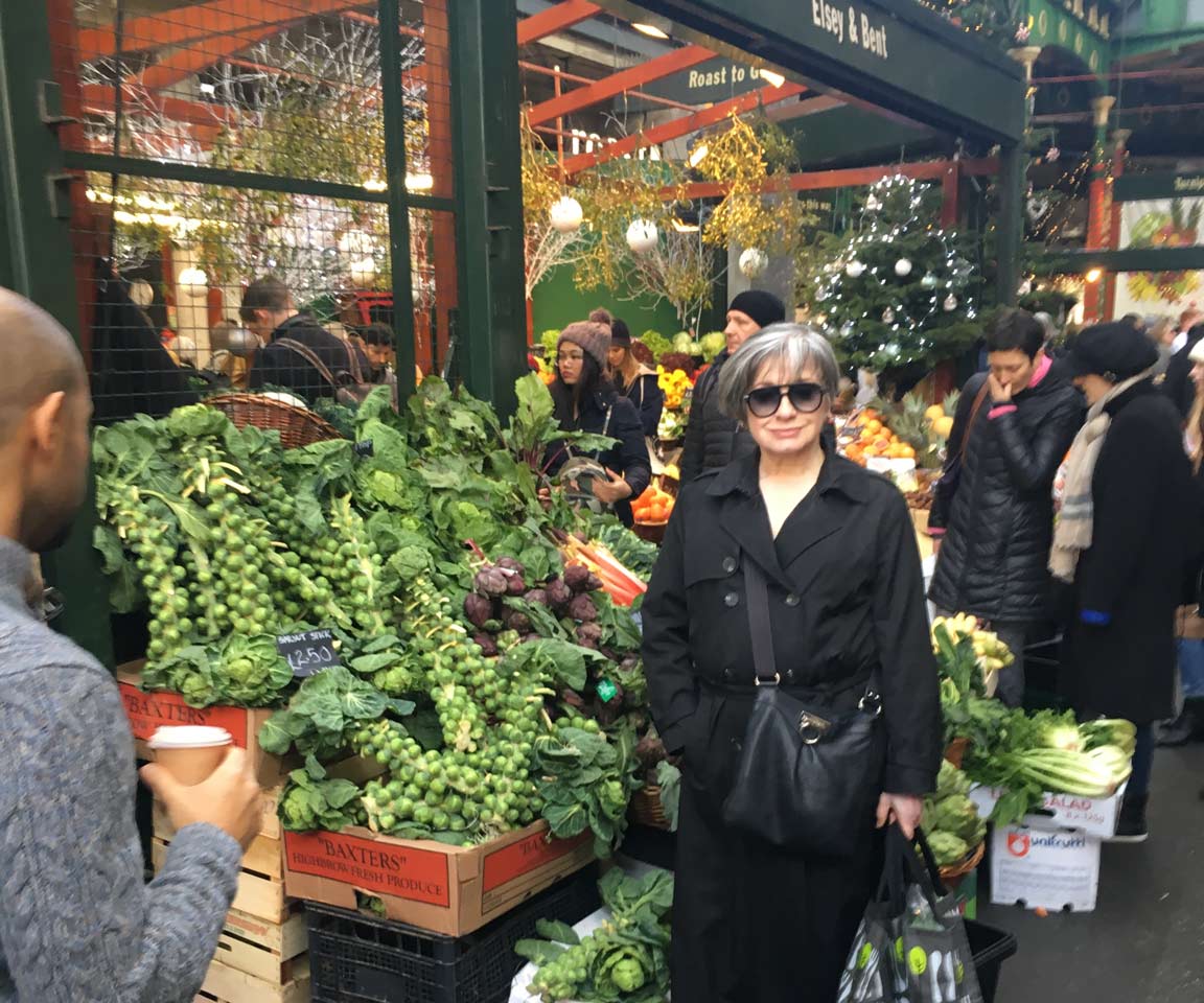 woman in black trench coat at Brussels sprout stand in Borough Market