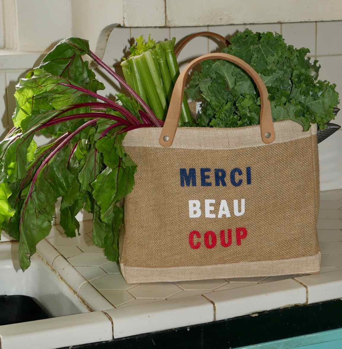 Apolis market bag with green leafy vegetables and message: Merci beaucoup