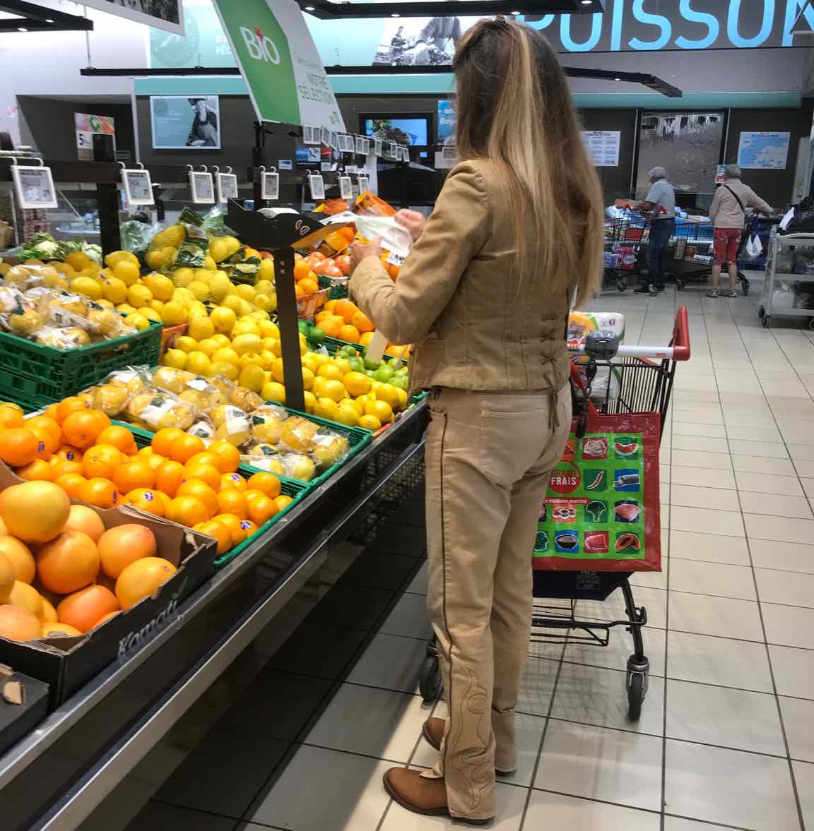 young woman in western wear buying  citrus fruit in market